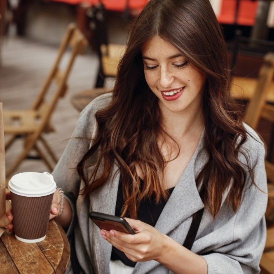 gorgeous-young-woman-holding-phone-and-smiling-wit-SBKQDZ9
