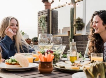 happy-friends-eating-vegan-food-with-wine-outdoors-GNYPXC7