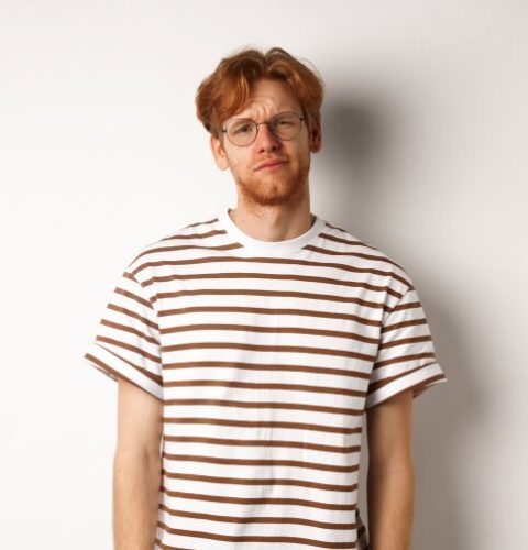 reluctant-and-unamused-redhead-young-man-staring-a-2ZK43U3