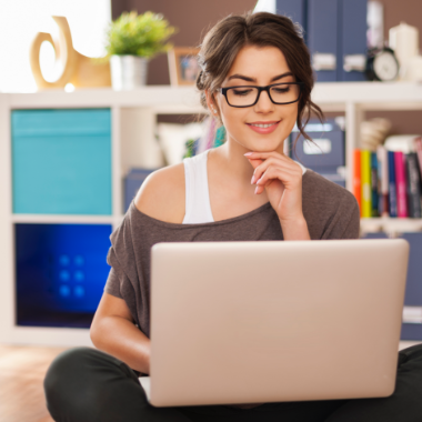 smiling-woman-using-laptop-on-floor-at-home-KTWBEPN