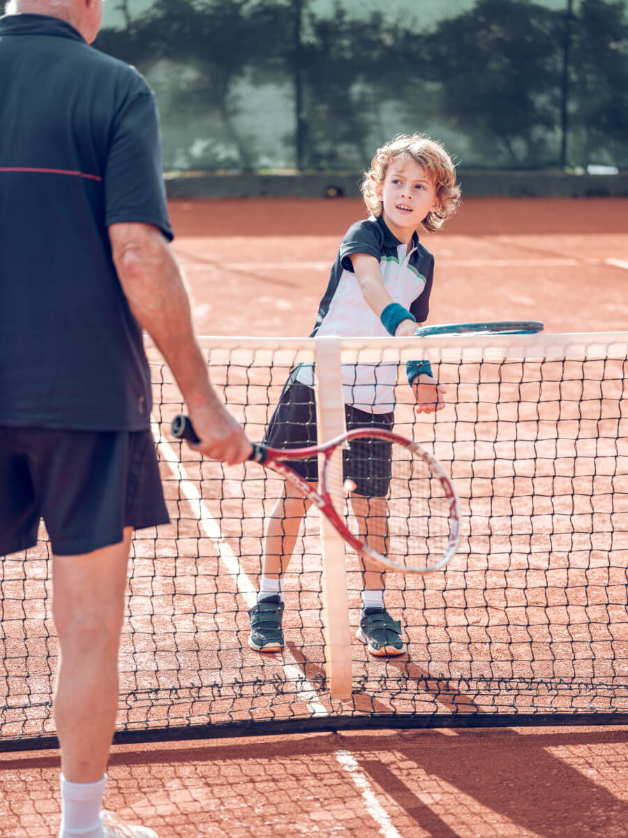 active-little-boy-practicing-tennis-with-crop-male-2022-02-03-23-30-10-utc