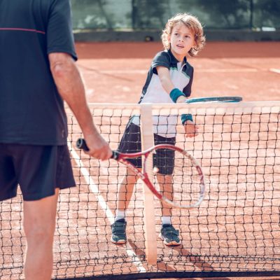active-little-boy-practicing-tennis-with-crop-male-2022-02-03-23-30-10-utc