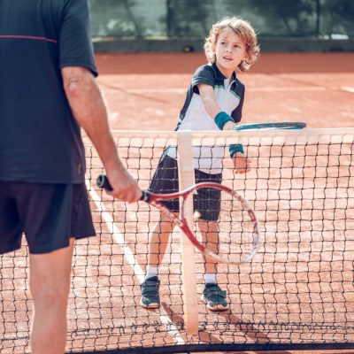 active-little-boy-practicing-tennis-with-crop-male-2022-02-03-23-30-10-utc