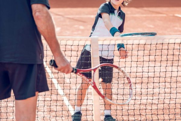 active-little-boy-practicing-tennis-with-crop-male-2022-02-03-23-30-10-utc